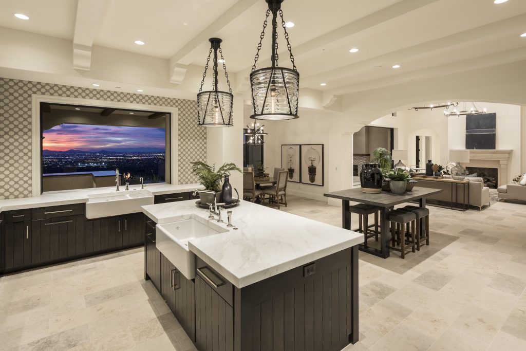 Open kitchen with dark cabinetry, white stone counters, pendant lighting, and sunset views at Andalusian Modern