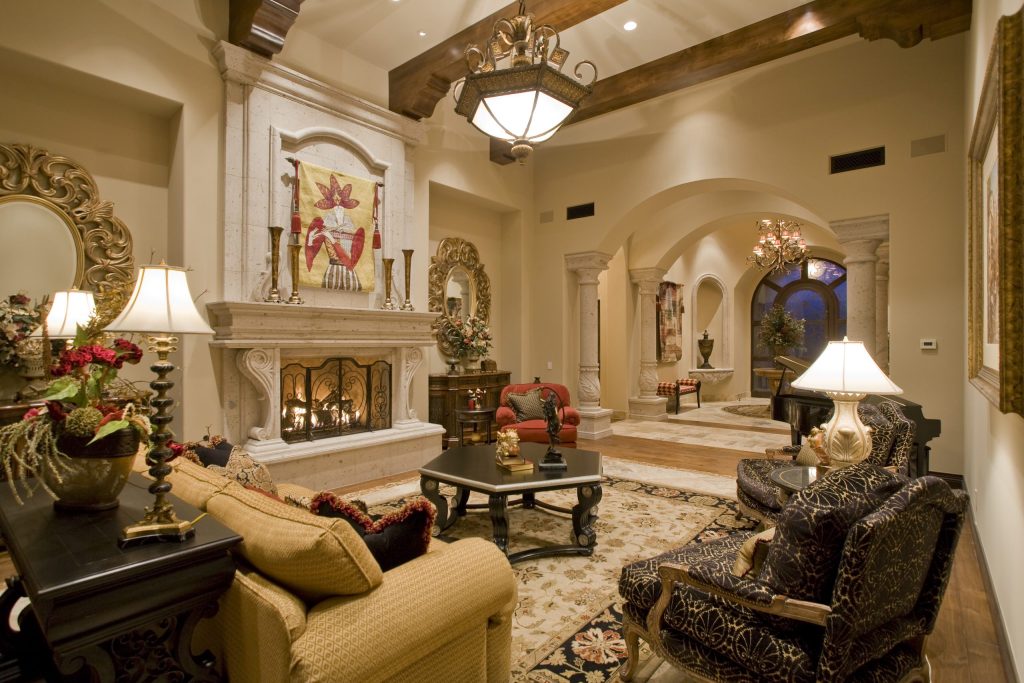 Living room with a carved stone fireplace, exposed beams, and arched openings at Mockingbird Estate