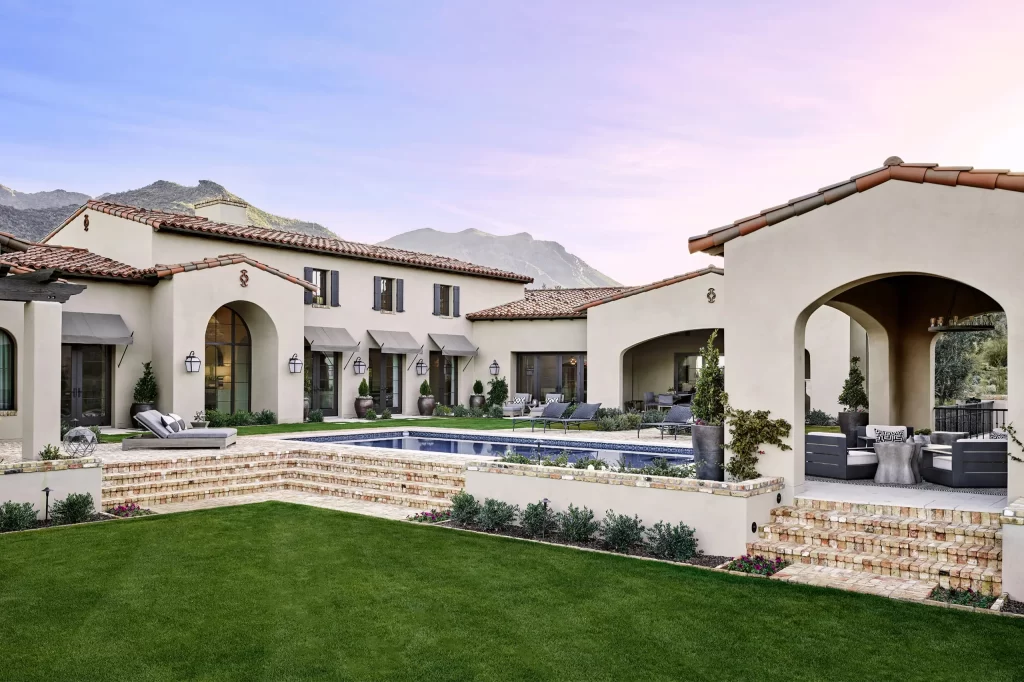 Stucco courtyard residence with pool, lawn, covered terrace, and mountain views