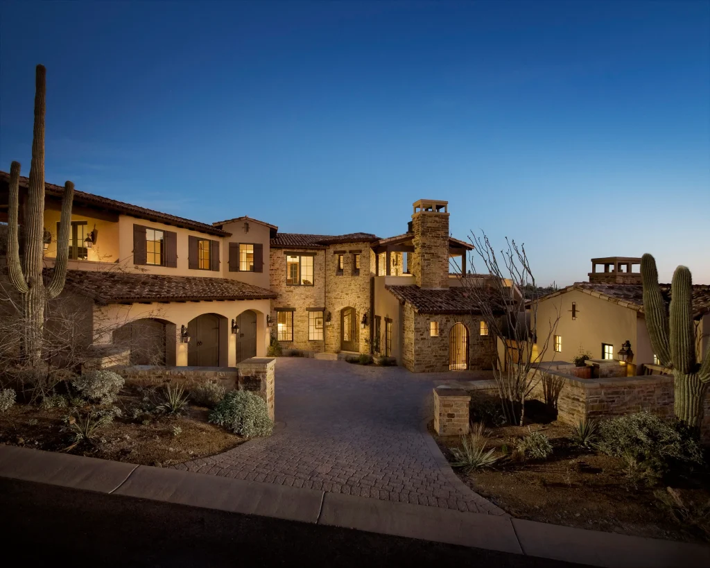 Stone and stucco front elevation of Desert Mountain Serenity at twilight